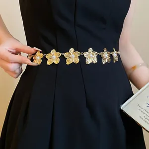 Dettaglio dell'elegante catena da vita a fiori in metallo dorato con perle su nero