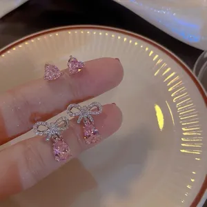 Close-up of pink heart studs and elegant bow teardrop earrings in Korean style