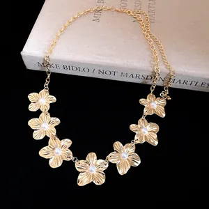 Dettaglio dei fiori in metallo dorato con perle su una cintura a catena vintage.