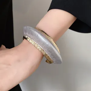 Close-up of chunky gold and silver textured open cuff bracelet with vertical grooves