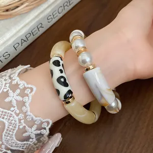 Close-up of bohemian layered bracelets featuring white pearls and dalmatian pattern acrylic