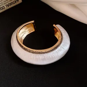 Close-up detail of elegant white textured open cuff bracelet with gold metallic interior