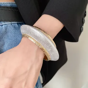 Close-up view of a minimalist textured metallic open bangle featuring gold and silver finishes