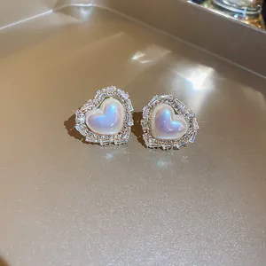 Close-up detail of Korean heart-shaped stud earrings with sparkling stones and iridescent core