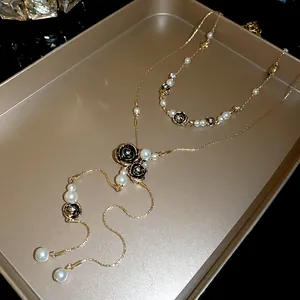 Exquisite close-up of vintage gold necklace with black roses and pearl tassels.