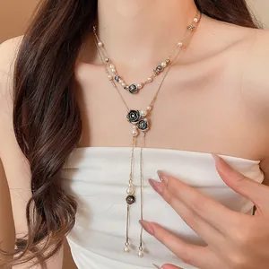 Close-up of a vintage rose and pearl tassel necklace on an elegant model's neck.