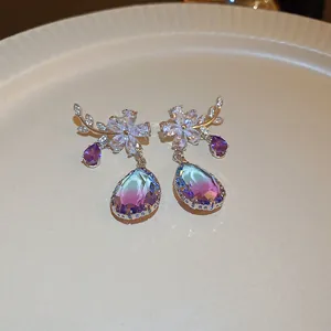 Close-up detail of elegant flower earrings with purple and blue gradient pear-shaped drops.