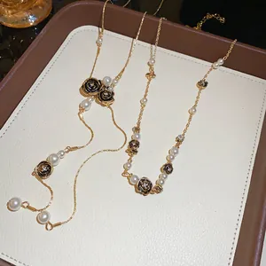 Detail of vintage gold-tone necklaces with black roses and pearls on a jewelry tray