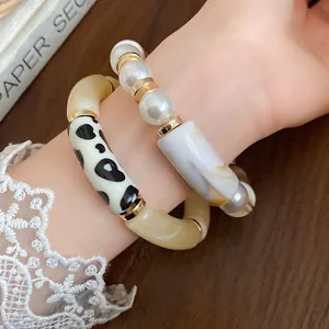 Elegant bohemian acrylic polka dot and faux pearl bracelet set worn on a female wrist