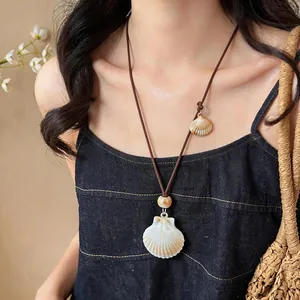 Detailed view of a bohemian shell necklace on a fashion model wearing a black top