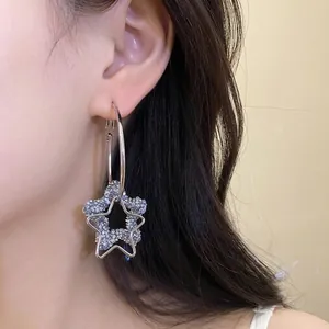 Fashionable silver needle hoop earrings featuring a sparkling resin star pendant worn on ear