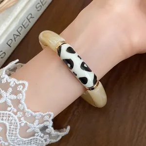 Bohemian acrylic bracelet with black polka dots and gold spacers on wrist detail