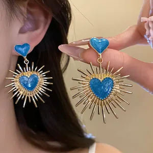 Vue détaillée de boucles d'oreilles vintage avec cœur bleu et motif soleil pour femme