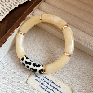 Close-up of a Bohemian acrylic bangle featuring cream segments and black polka dot details.