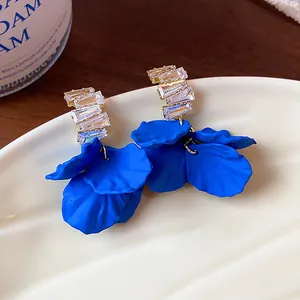 Primo piano di orecchini a petalo in acrilico blu Klein con zirconi scintillanti
