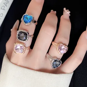 Detailed view of multiple heart-shaped and square rhinestone open rings on woman's fingers