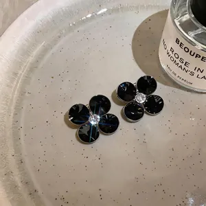 Elegant black flower stud earrings featuring four glossy petals and a central crystal