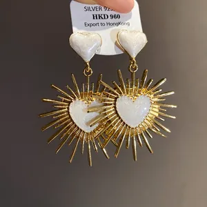 Gros plan de boucles d'oreilles cœur vintage dorées avec émail blanc scintillant