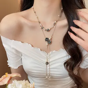 Close-up detail of a vintage style black rose and pearl tassel necklace worn on a model.