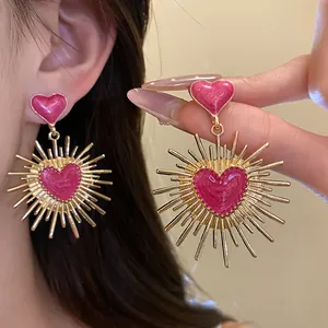 Détail de boucles d'oreilles cœur vintage en émail rose avec rayons dorés