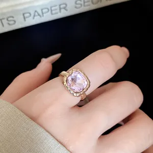 Macro detail view of an elegant rose gold ring with a large square pink crystal on a finger