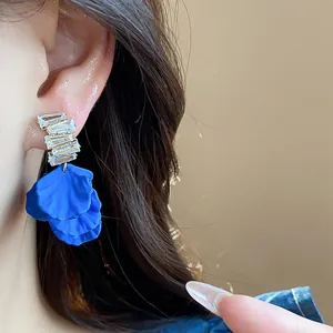 Dettaglio di orecchini a petalo in acrilico blu Klein con borchie in zircone.