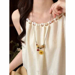 Close-up of a handmade yellow flower pendant necklace with wooden beads on cord