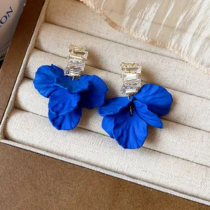 Dettaglio ravvicinato di eleganti orecchini a petalo in acrilico blu Klein con zirconi