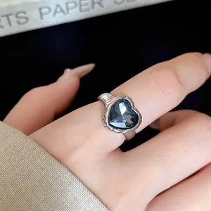 Close-up of elegant silver open ring featuring a deep blue heart crystal detail
