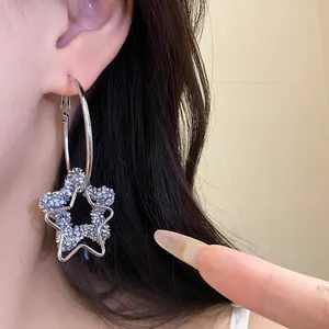 Close-up detail of stylish silver hoop earrings with a sparkling blue resin star pendant