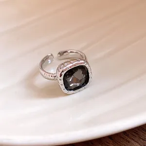 Macro view of a silver open ring featuring a faceted dark stone and ribbed texture detail.