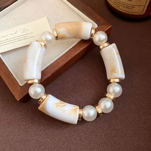 Close-up of bohemian acrylic bracelet with marbled tubes and elegant faux pearls