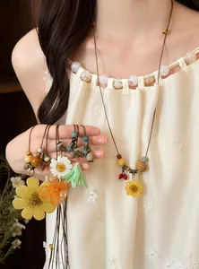 Detail view of handmade dried flower resin pendants with wooden beads on leather cord