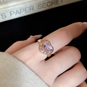 Close-up of elegant gold heart ring with pink crystal and textured metal details