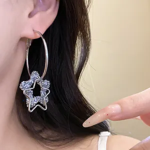 Detailed view of silver hoop earrings featuring star pendant with blue resin crystals