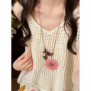Detail of a boho necklace with wood beads and a large pink everlasting flower pendant.