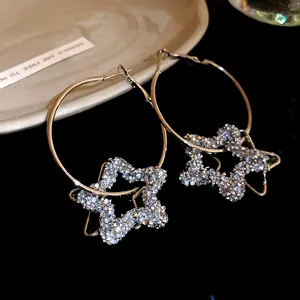 Close-up of minimalist silver hoop earrings featuring shimmering resin star pendants.
