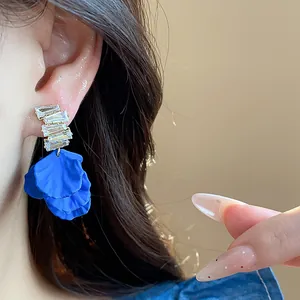 Primo piano di orecchini a petalo in acrilico blu Klein con zirconi cubici