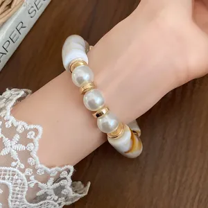Detail view of a bohemian bracelet with pearls and marbled acrylic beads on a wrist.