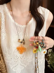 Close-up of handmade leather cord necklaces with wooden beads and flower charms