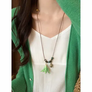 Detail of handmade green ceramic lily flower pendant necklace on brown leather cord
