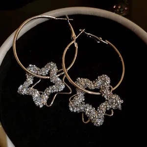 Close-up of sparkling resin star pendant hoop earrings on black velvet lining