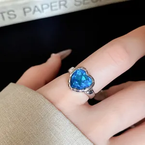 Close-up detail of a silver-toned open ring with a vibrant blue heart-shaped gemstone