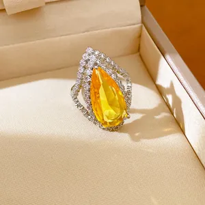 Detailed close-up of pear-cut yellow zircon ring featuring vintage court style diamond halo