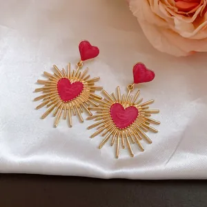 Boucles d'oreilles cœur vintage avec émail rouge et motif soleil sur fond de soie.