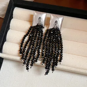 Gros plan de boucles d'oreilles carrées en argent avec de longs pompons en perles noires
