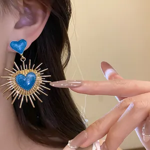 Vue détaillée des boucles d'oreilles vintage cœur en émail bleu et pointes dorées.