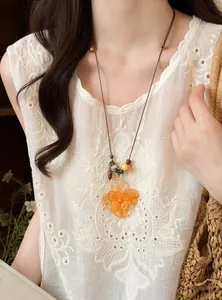 Detail shot of a handmade orange flower pendant necklace with leather cord and beads