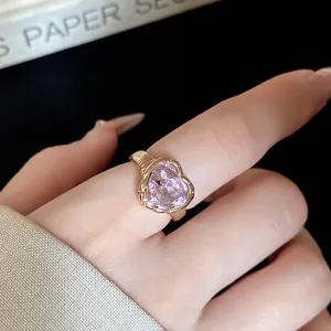 Detail view of heart-shaped pink crystal open ring in polished gold plating finish