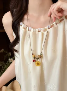 Close-up of bohemian leather cord necklace with pressed sunflower pendant and wooden beads.